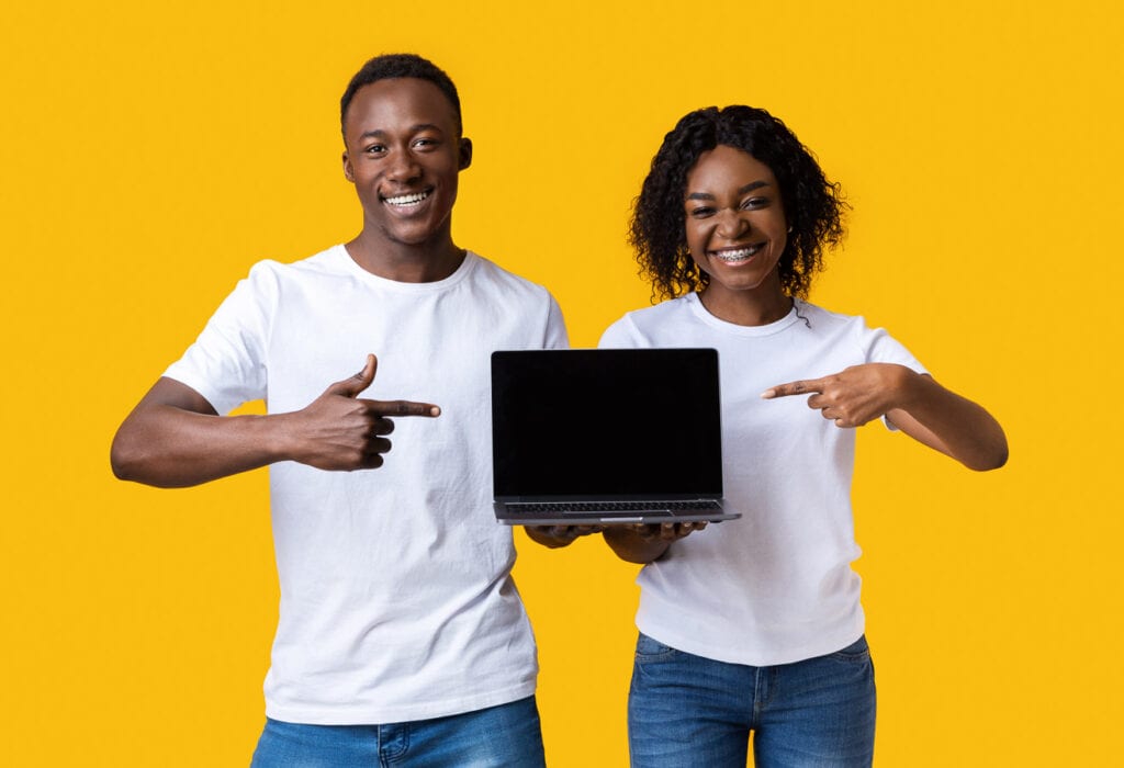 Two young black individuals pointing at blank laptop screen