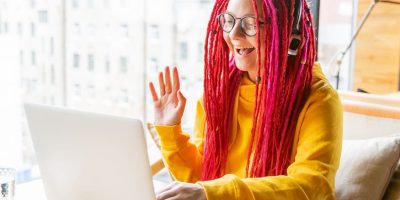 Woman in headphones waving at her laptop